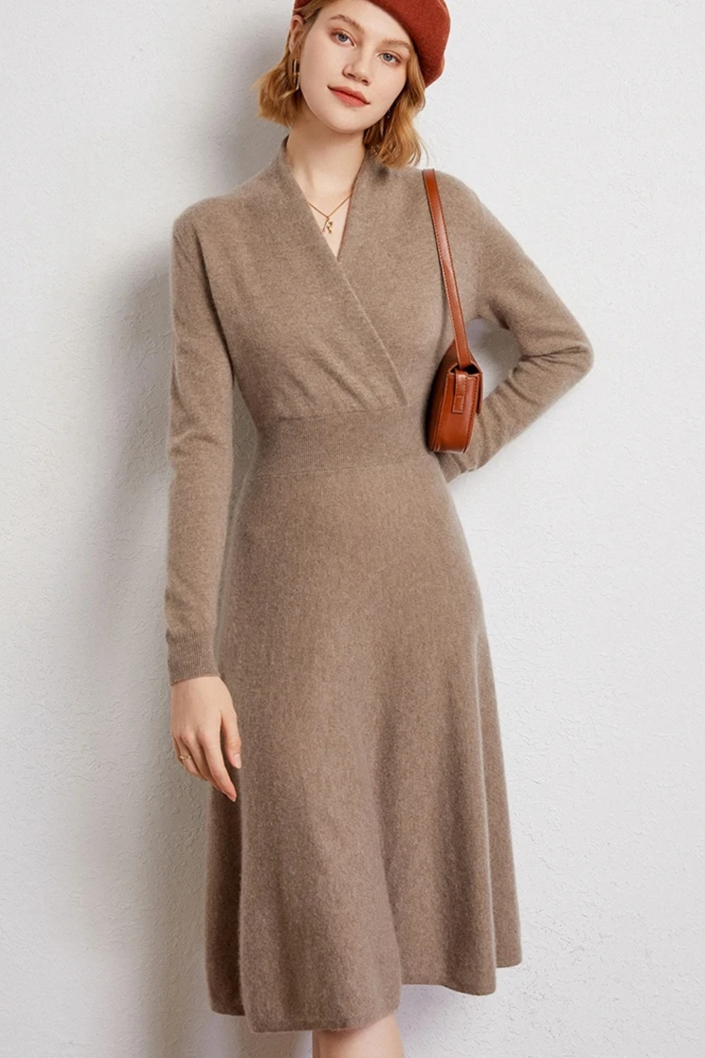 Woman wearing a beige wrap dress and red beret on a plain background