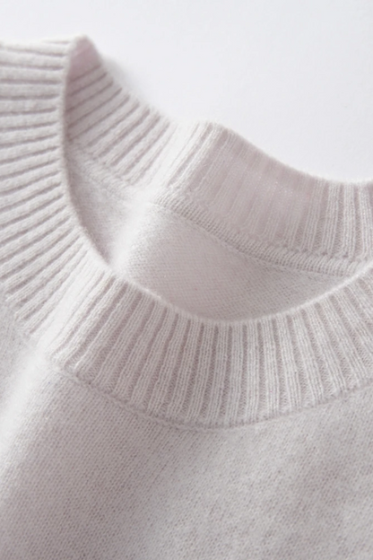 Close-up of a cream sweater collar on a white background.