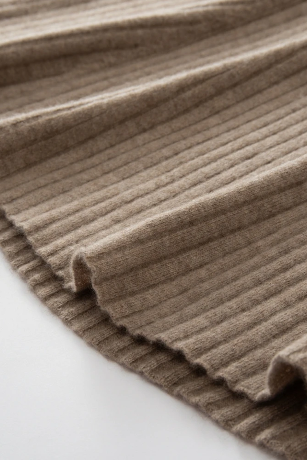 Close-up of a ribbed camel coloured dress on a light background