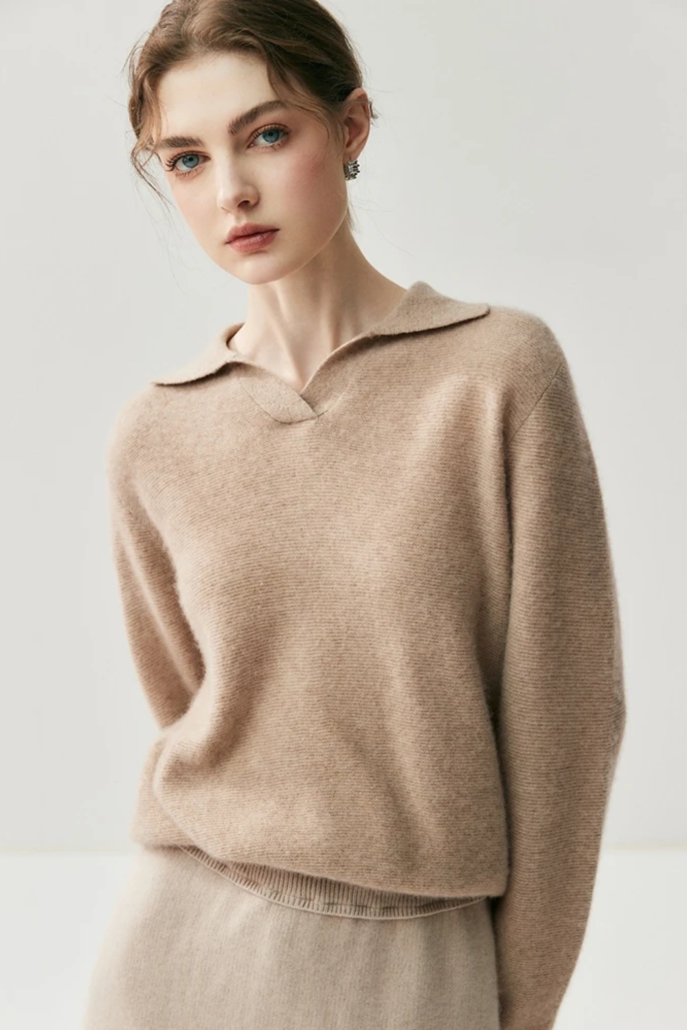 Woman wearing a camel coloured sweater against a plain background