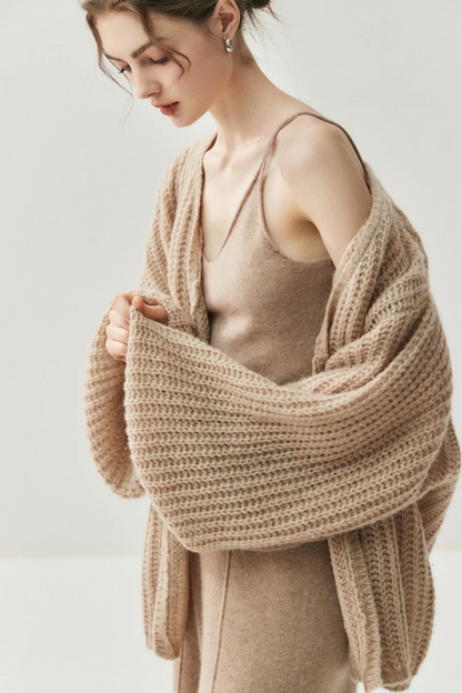 Woman wearing a camel knit cardigan and pants on a white background