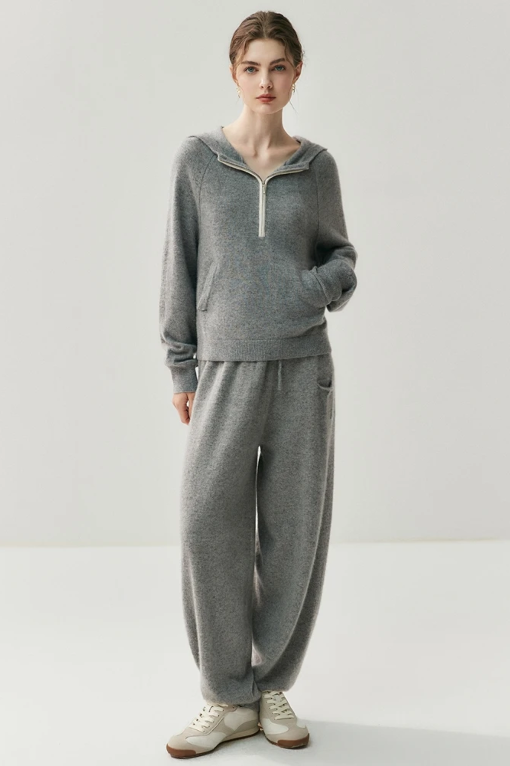 Person wearing a gray sweater and pants set on a white background