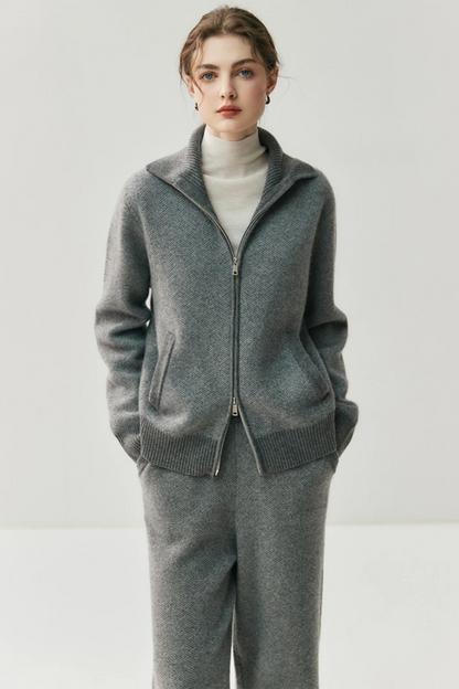 Person wearing a gray zip-up sweater over a white turtleneck on a plain background