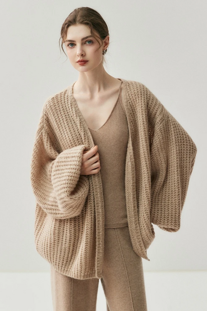 Woman wearing a camel knit cardigan and pants on a white background