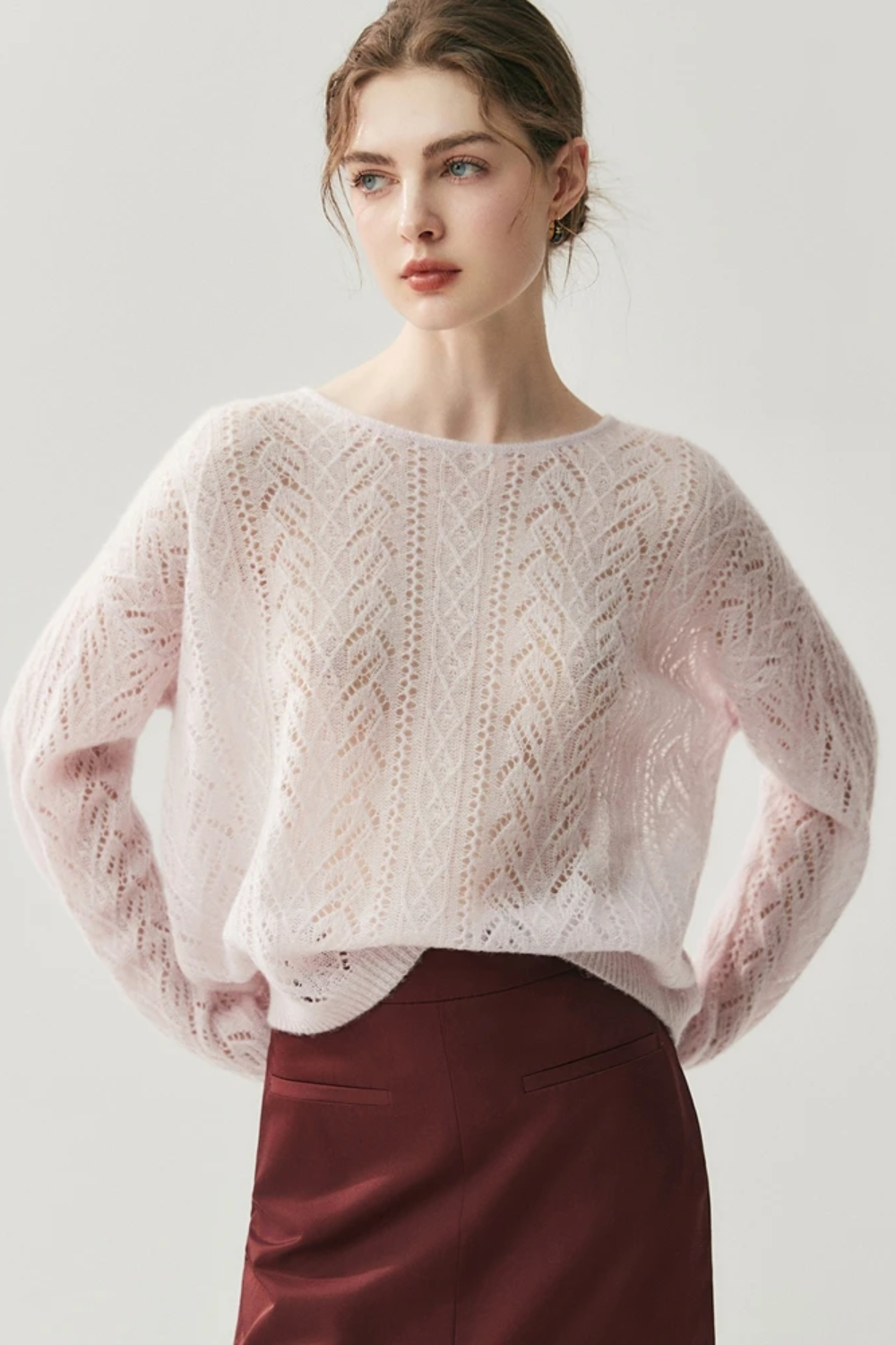 Woman wearing a light pink knitted sweater against a white background