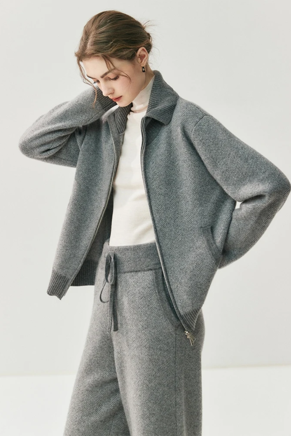 Person wearing a gray coat and pants on a white background