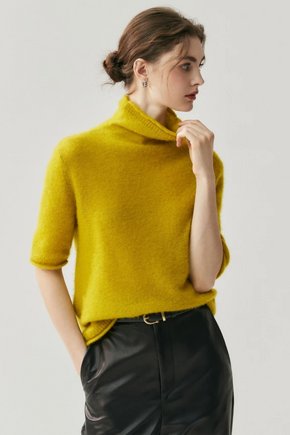Woman wearing a mustard yellow sweater against a plain background