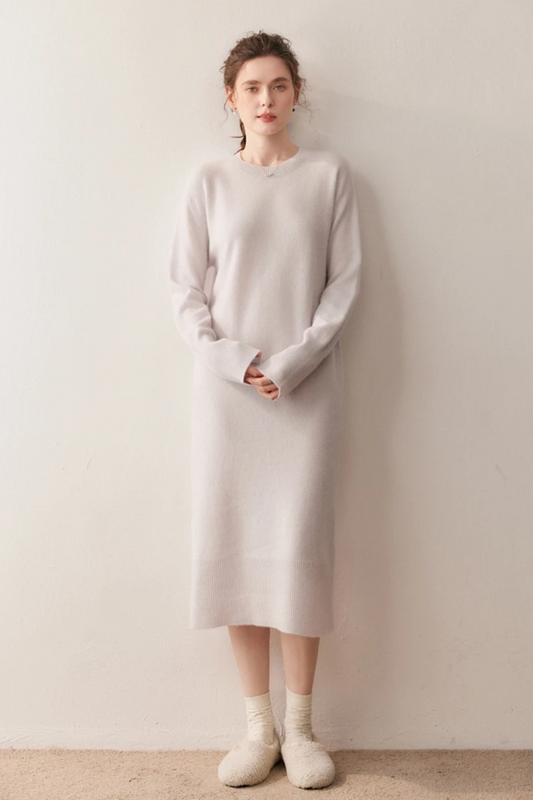 Woman wearing a long cream dress against a plain background.