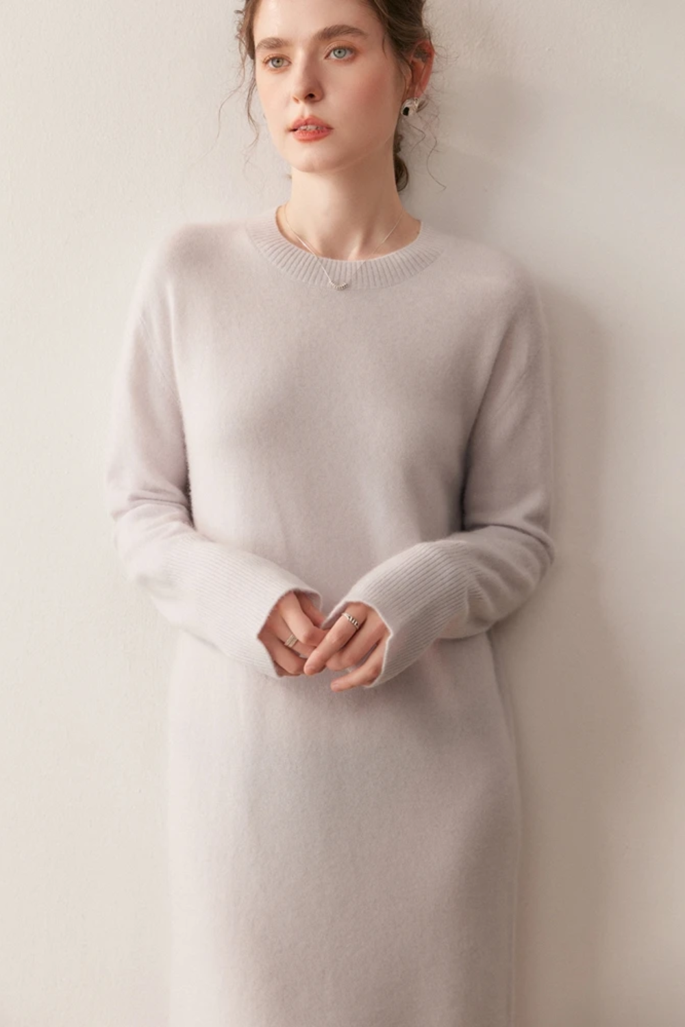 Woman wearing a long cream dress against a plain background.