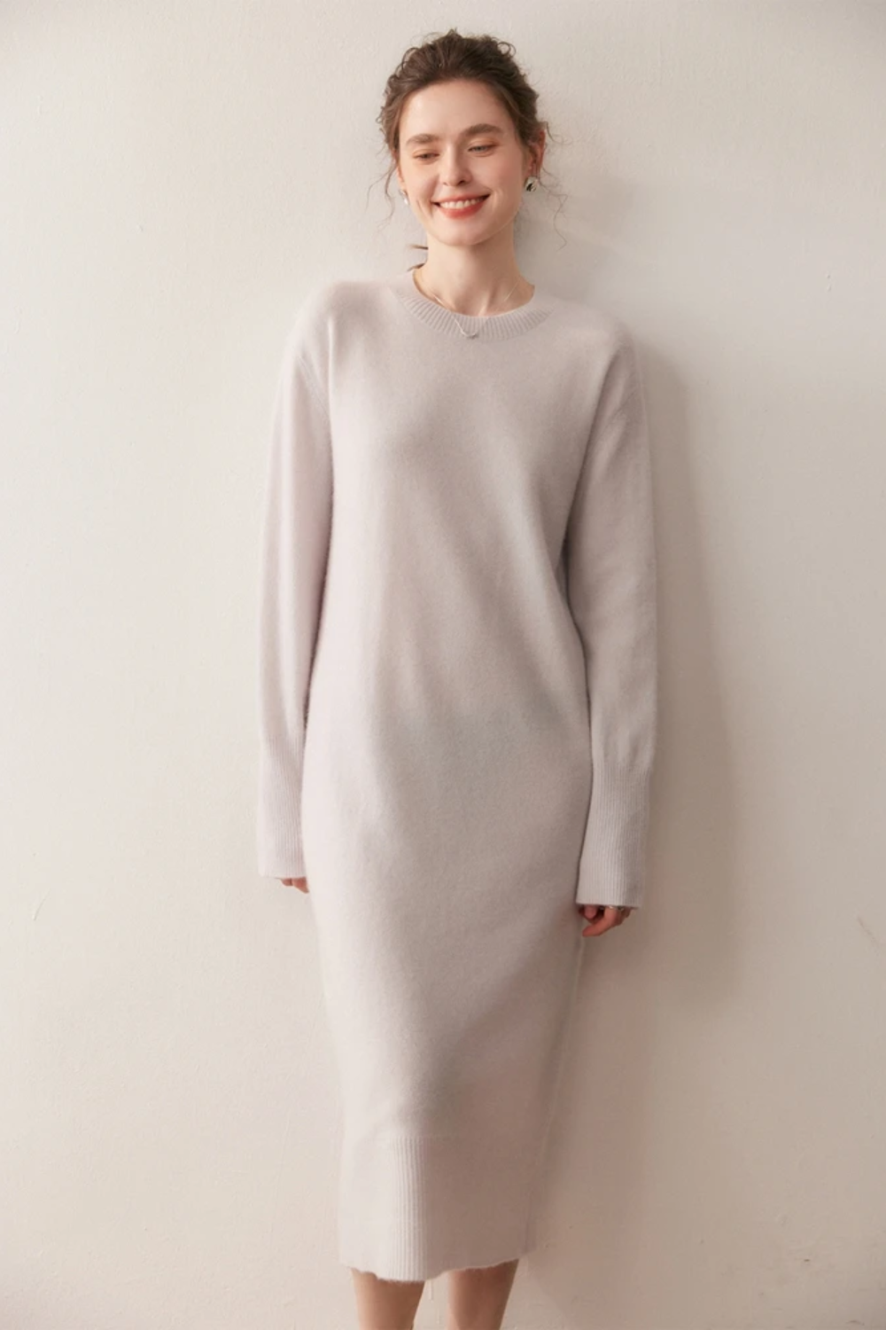 Woman wearing a long cream dress against a plain background.