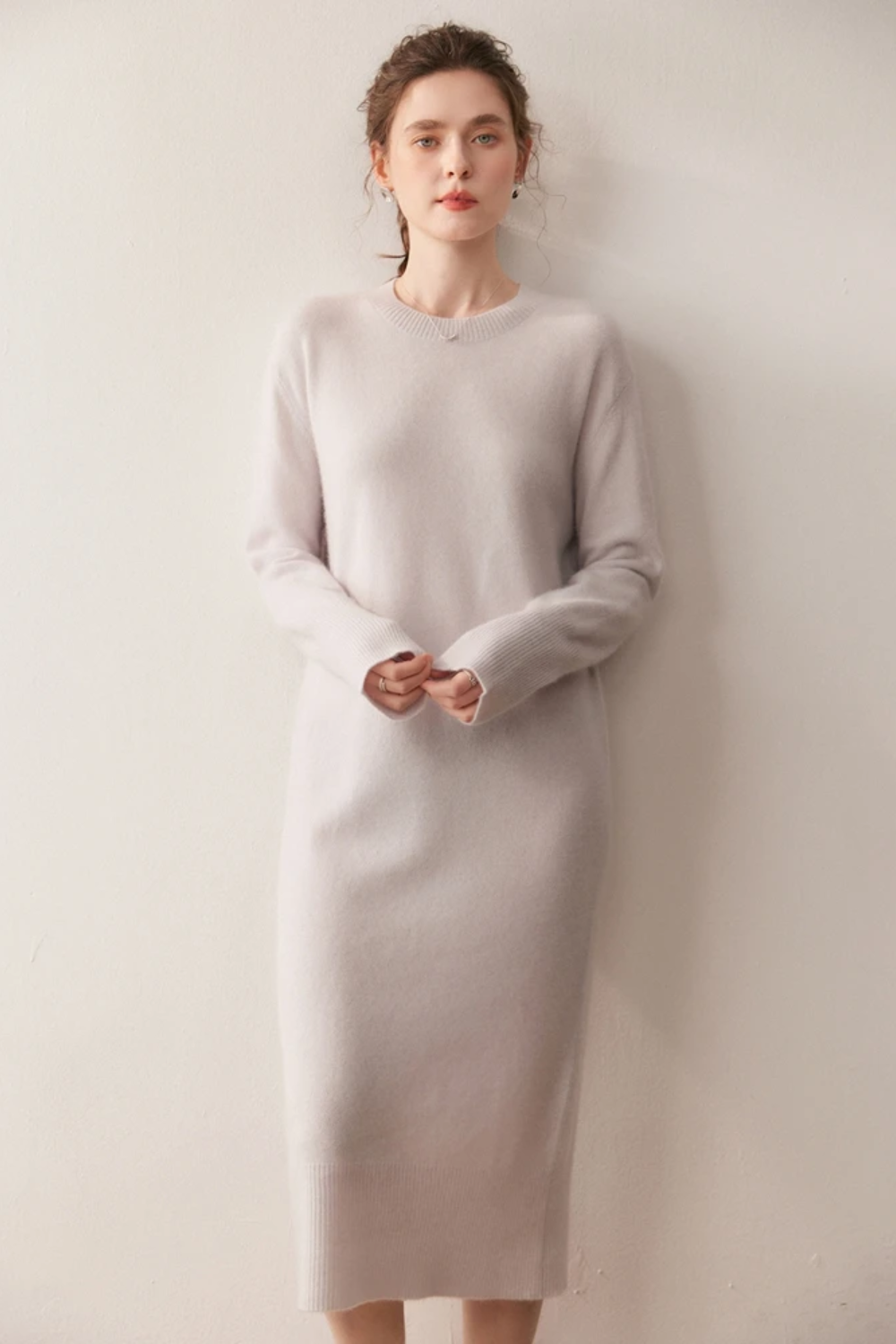 Woman wearing a long cream dress against a plain background.