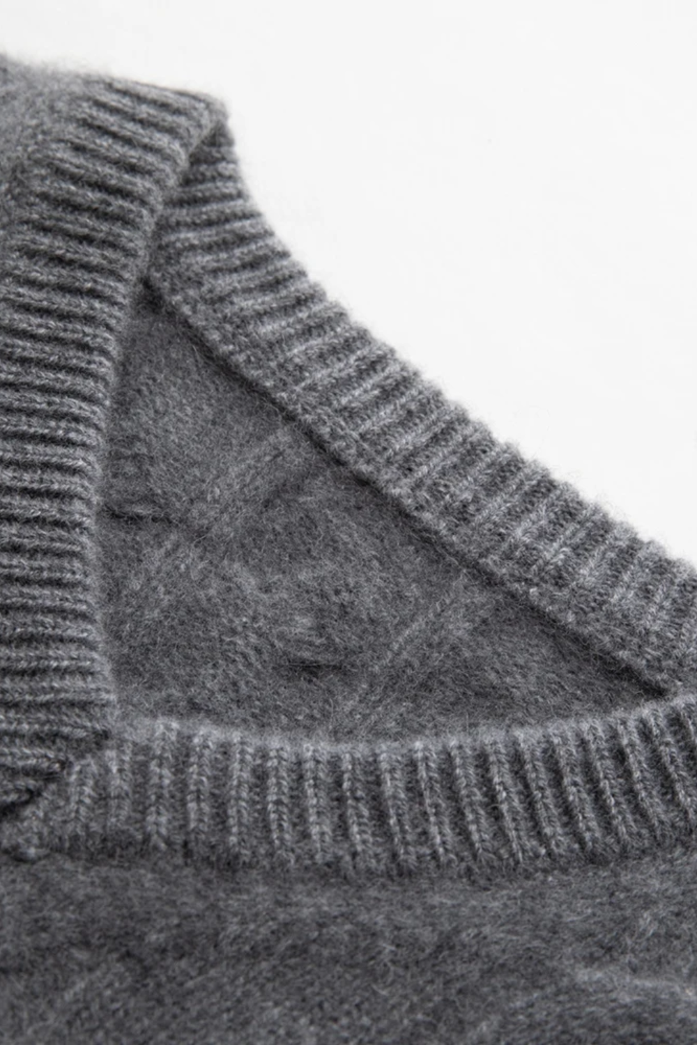 Close-up of a gray knitted sweater with a patterned texture.