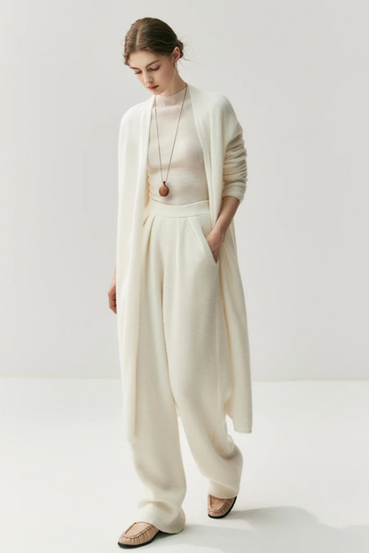 Woman wearing a white outfit with a ahite long cardigan on a white background