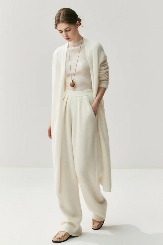 Woman wearing a white outfit with a ahite long cardigan on a white background