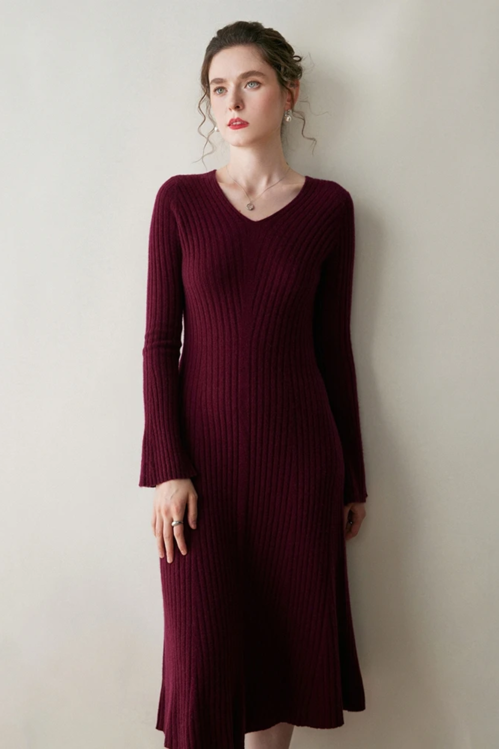 Woman wearing a burgundy ribbed dress against a plain background