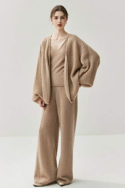 Woman wearing a camel knit cardigan and pants on a white background