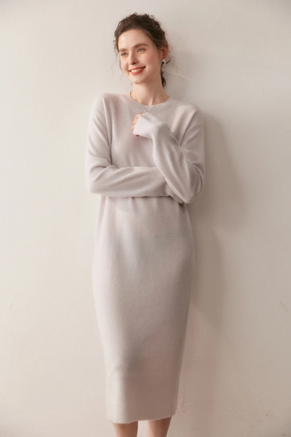 Woman wearing a long cream dress against a plain background.