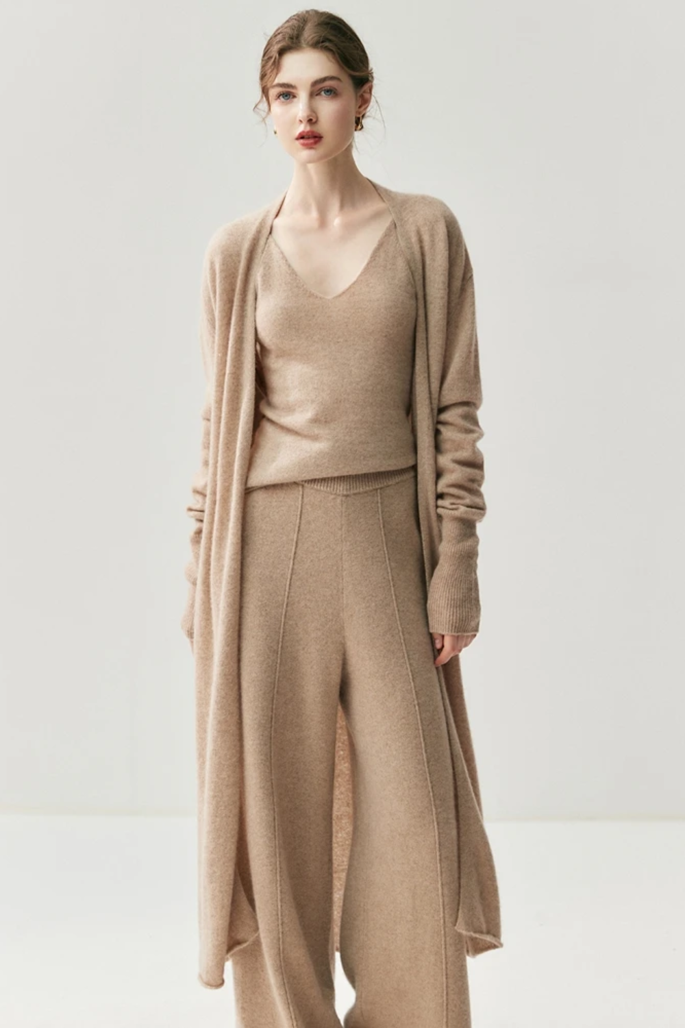 Woman wearing a camel sweater and pants set on a white background