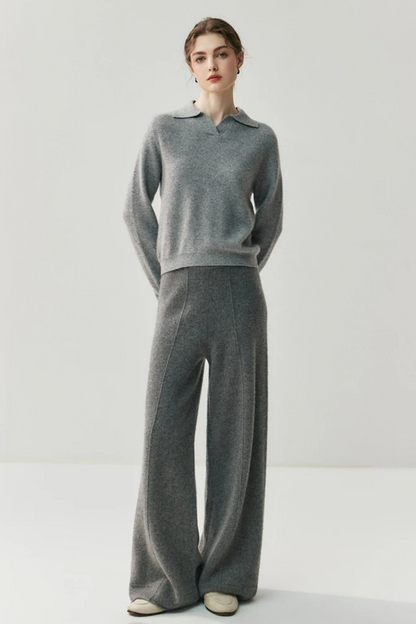 Woman wearing a gray collared sweater and pants against a white background