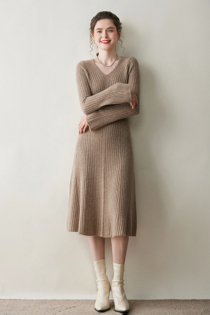 Woman wearing a camel coloured ribbed dress against a plain wall