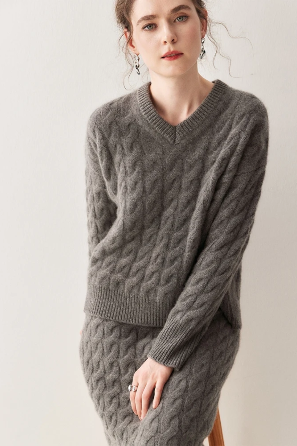 Model wearing a grey knotted sweater and skirt set