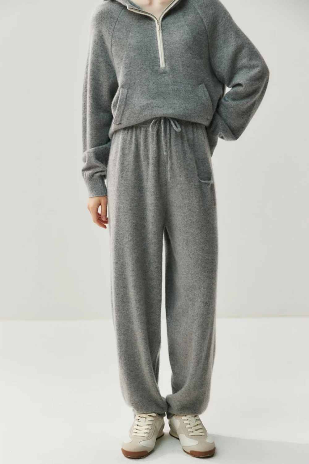 Person wearing a gray sweater and pants set on a white background