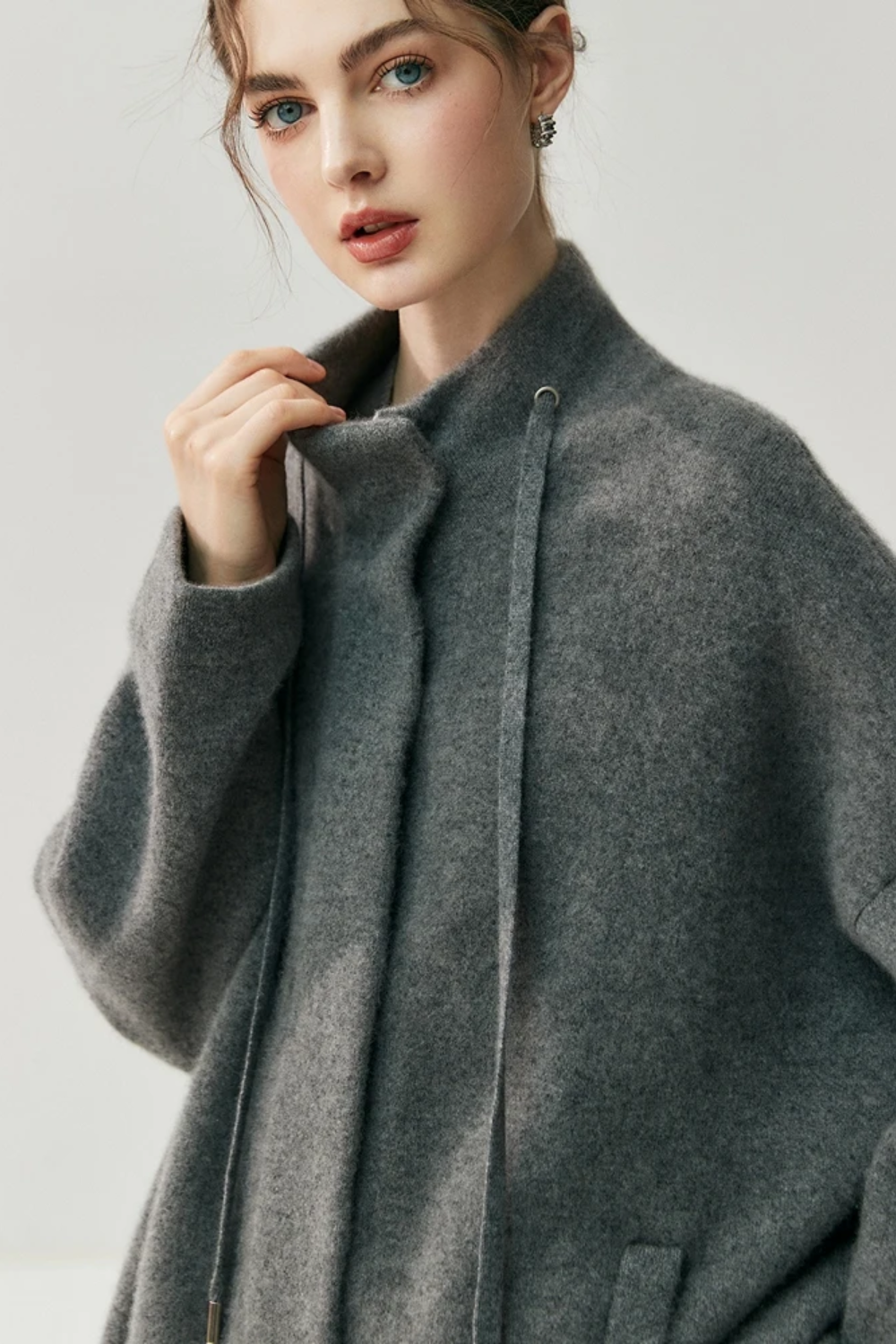 Woman wearing a gray cardigan against a plain background