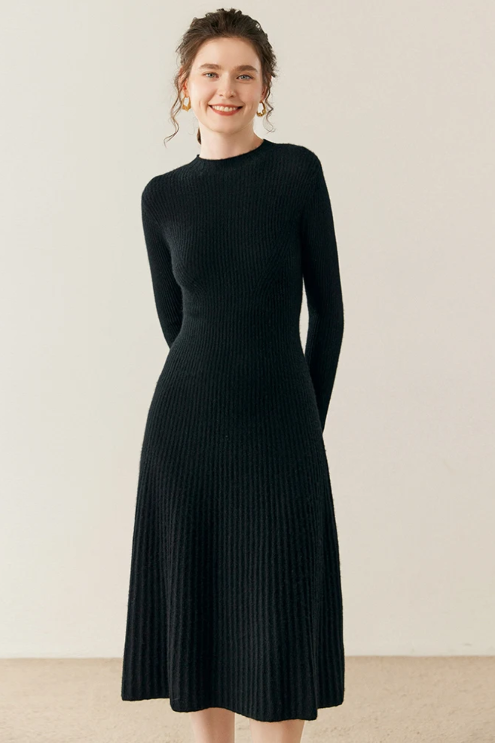 Woman wearing a black ribbed dress against a plain background