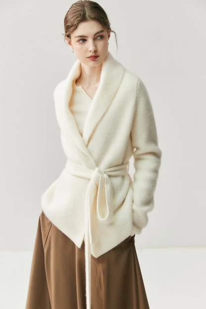 Woman wearing a white cardigan, beige blouse, brown skirt, and beige shoes on a white background