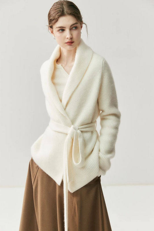 Woman wearing a white cardigan, beige blouse, brown skirt, and beige shoes on a white background