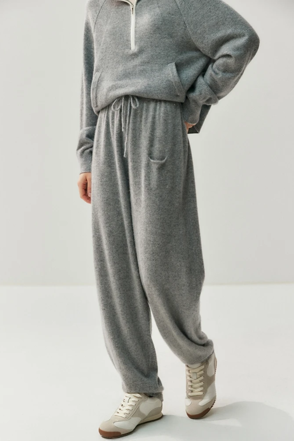 Person wearing a gray sweater and pants set on a white background
