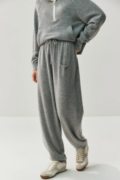 Person wearing a gray sweater and pants set on a white background