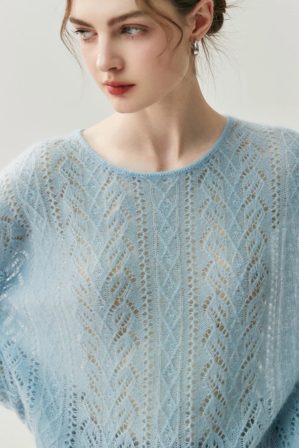Woman wearing a light blue knitted sweater with a subtle pattern against a plain background