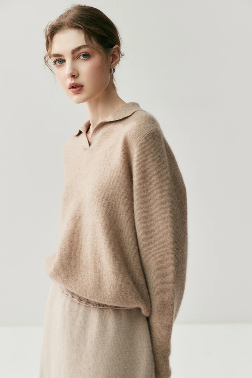 Woman wearing a camel coloured sweater against a plain background