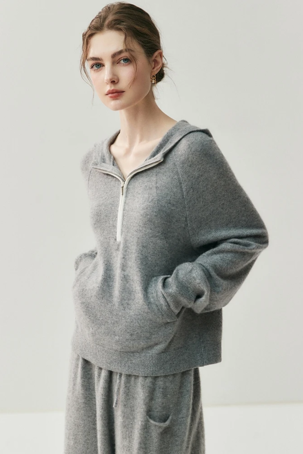Person wearing a gray sweater and pants set on a white background