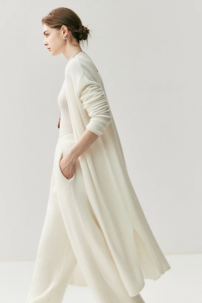 Woman wearing a long,white cardigan against a plain background