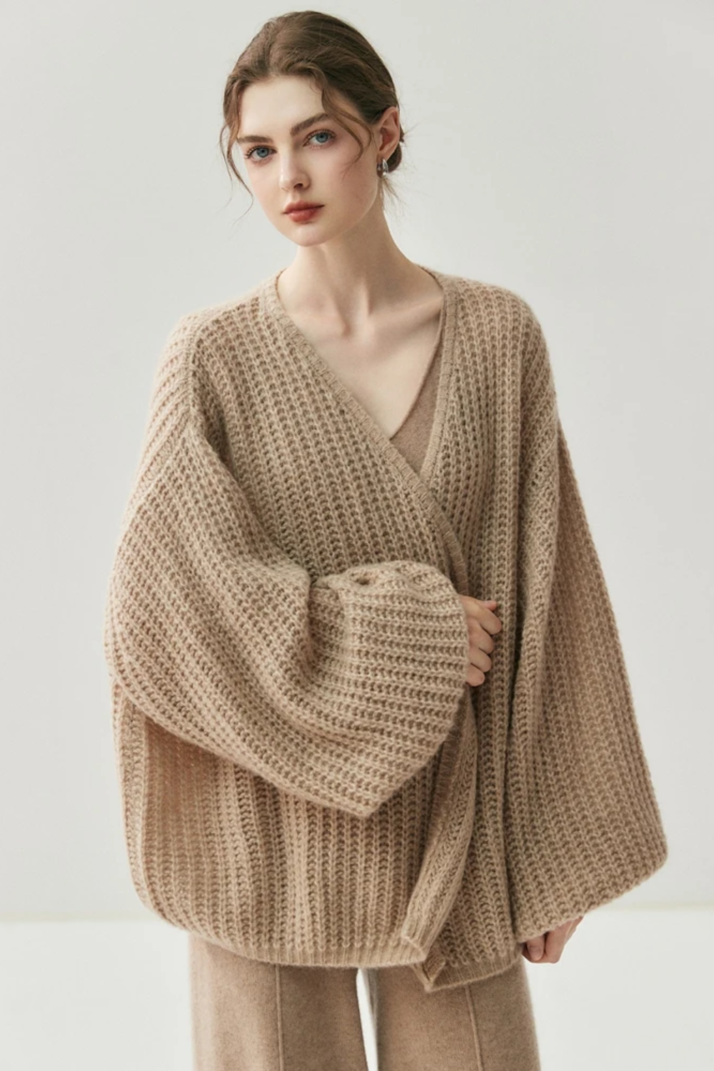 Woman wearing a camel knit cardigan and skirt on a white background