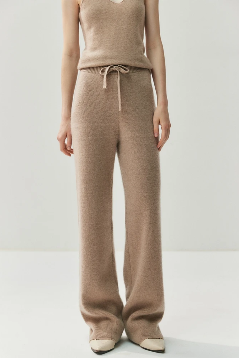 Woman wearing a camel-coloured knit outfit on a white background