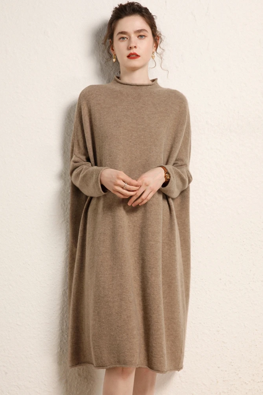 Woman wearing a camel coloured dress against a plain background