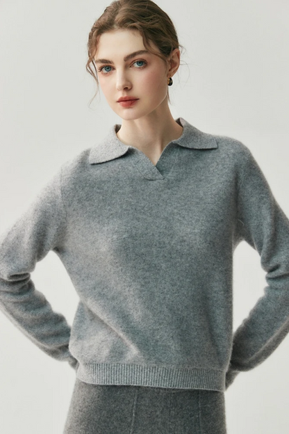 Woman wearing a gray collared sweater and pants against a white background