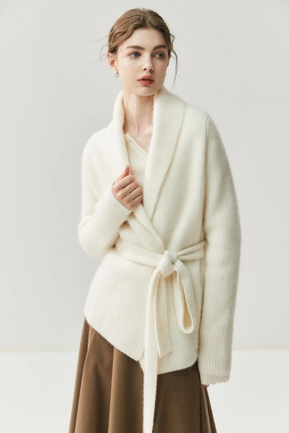 Woman wearing a white cardigan, beige blouse, brown skirt, and beige shoes on a white background