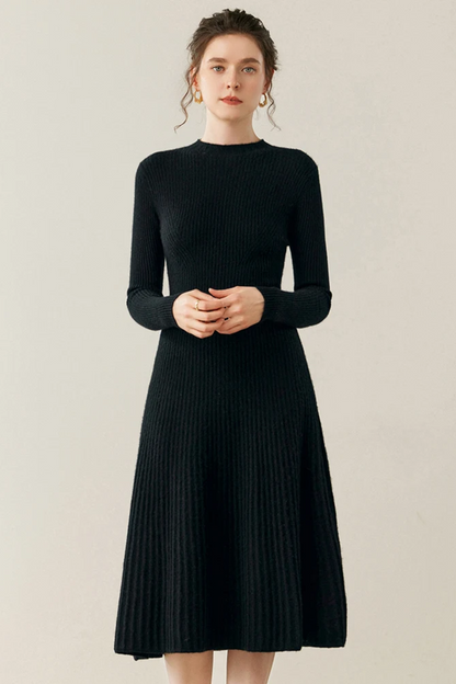 Woman wearing a black ribbed dress against a plain background