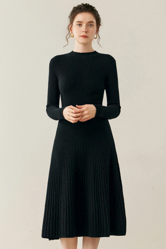 Woman wearing a black ribbed dress against a plain background