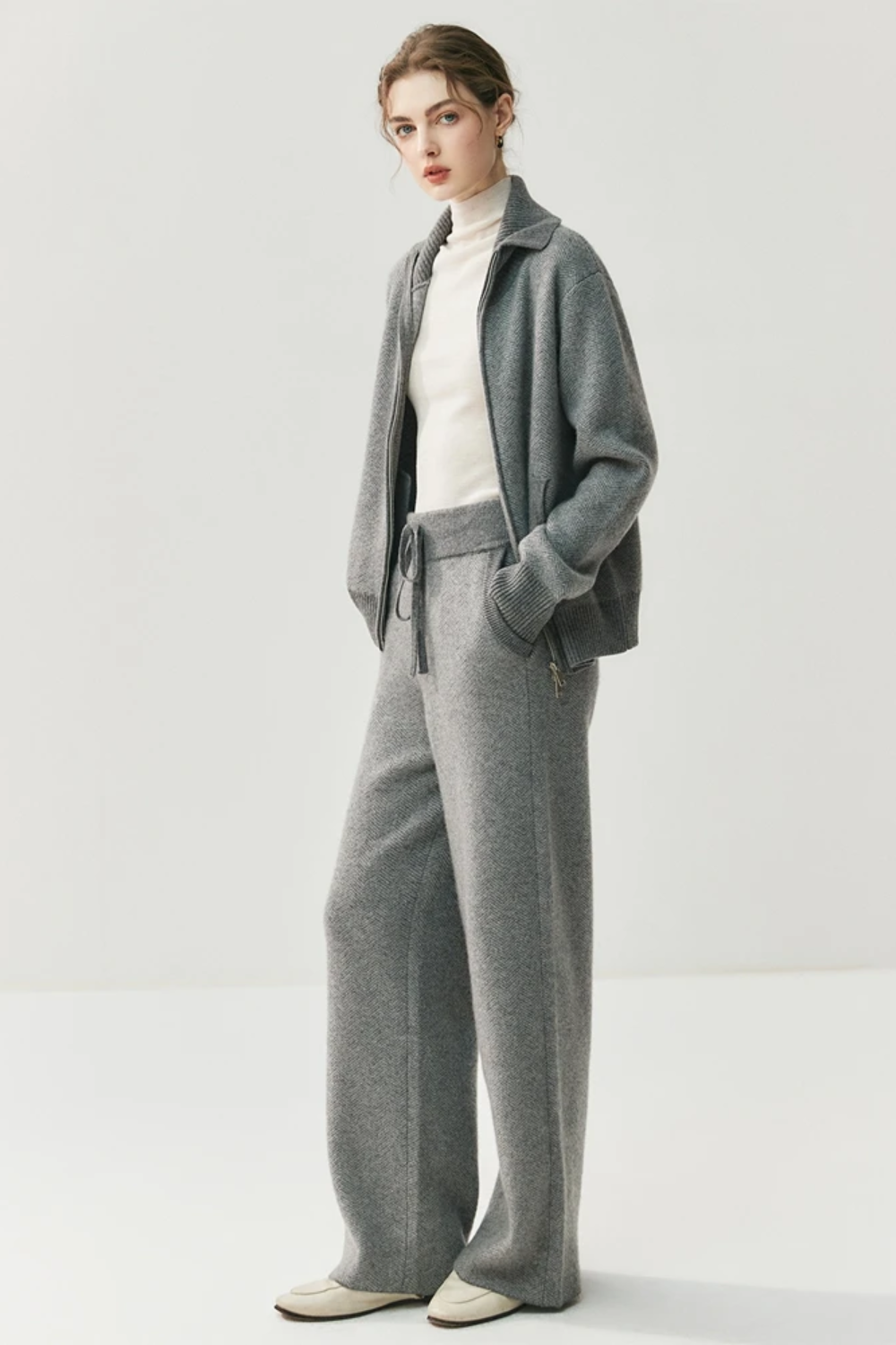 Person wearing a gray suit with a white shirt on a light gray background