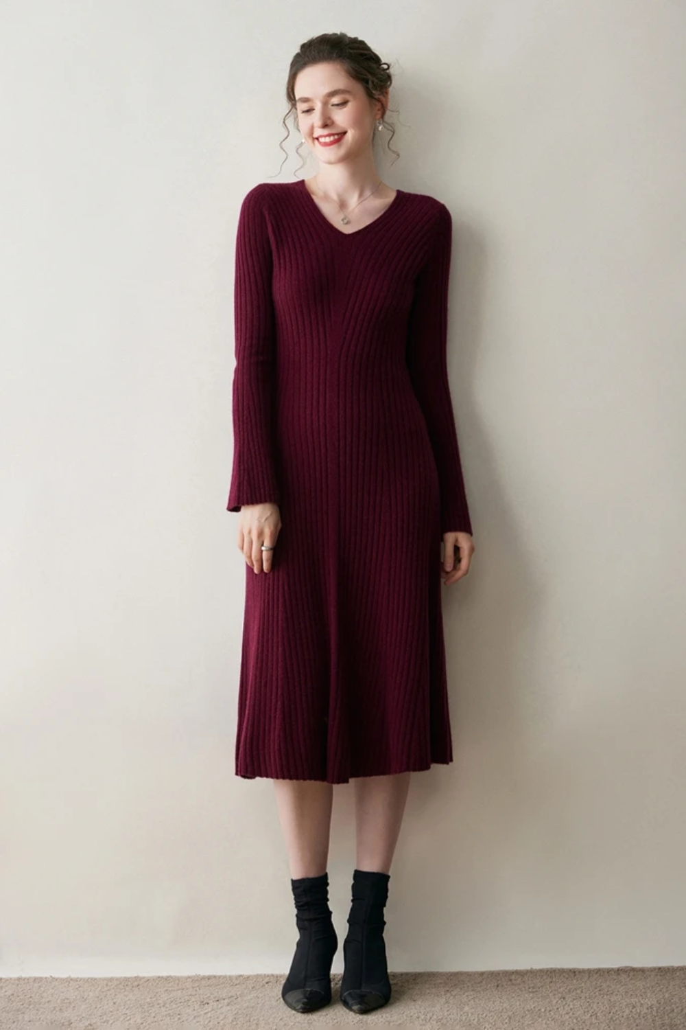 Woman wearing a burgundy ribbed dress against a plain background