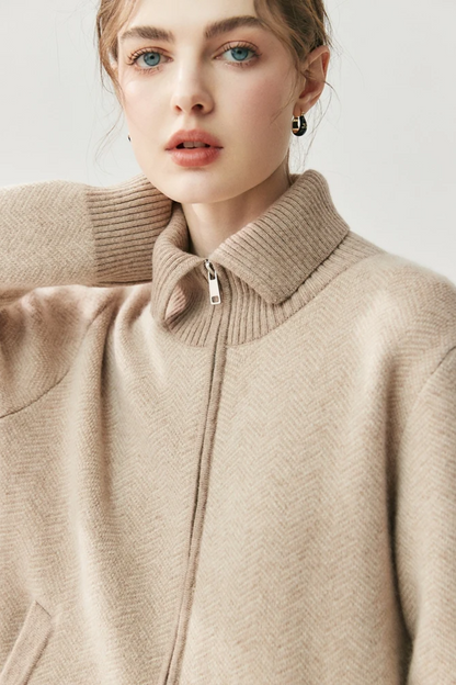 Close-up of a person wearing a camel zip-up sweater against a light background