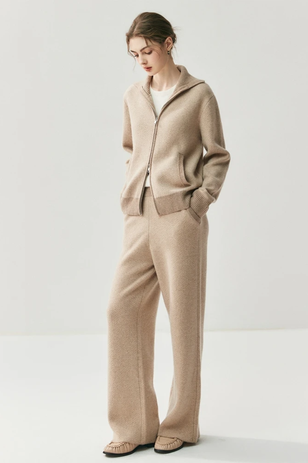 Woman wearing a camel cardigan and pants on a white background