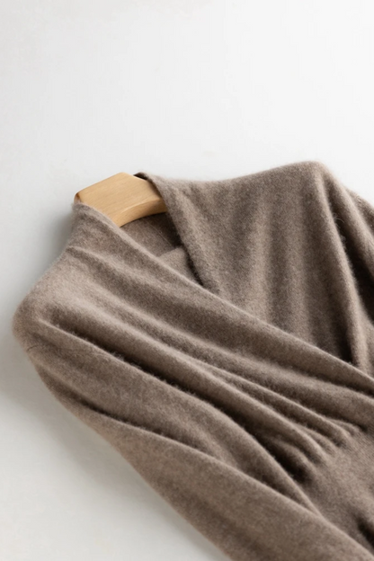 Beige wrap dress draped over a wooden hanger on a white background