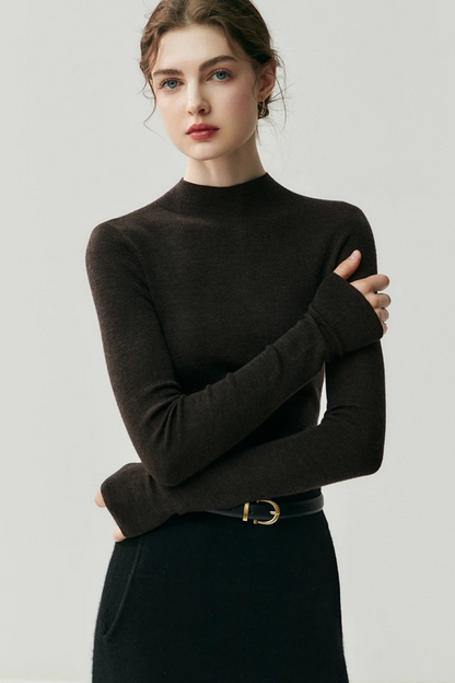 Woman wearing a dark brown turtleneck sweater against a plain background