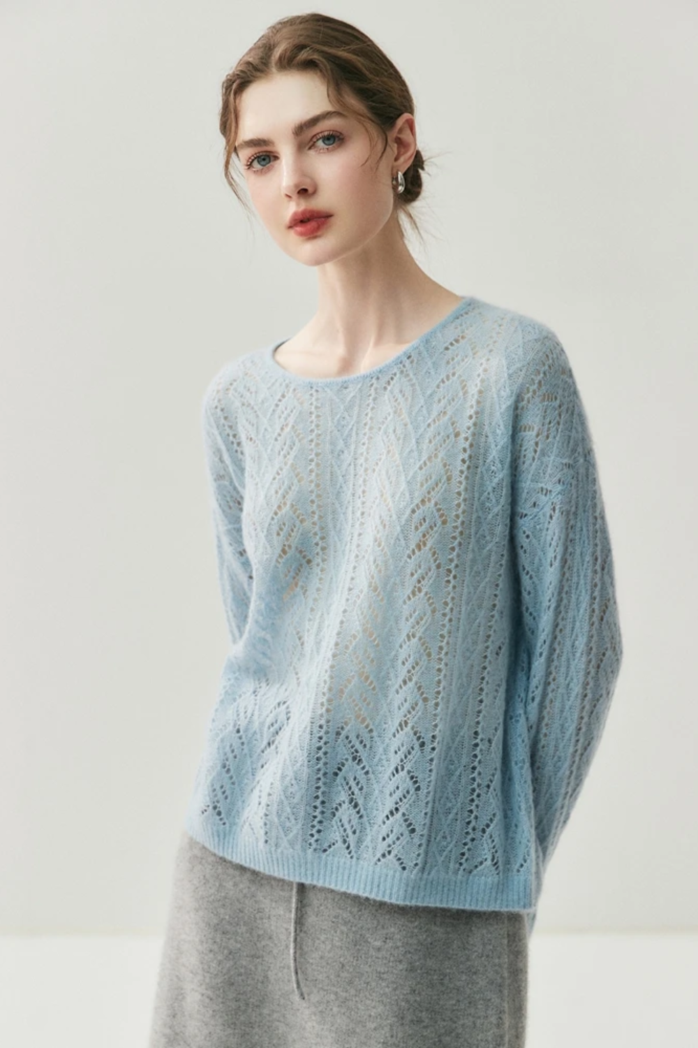 Woman wearing a light blue knitted sweater on a plain background